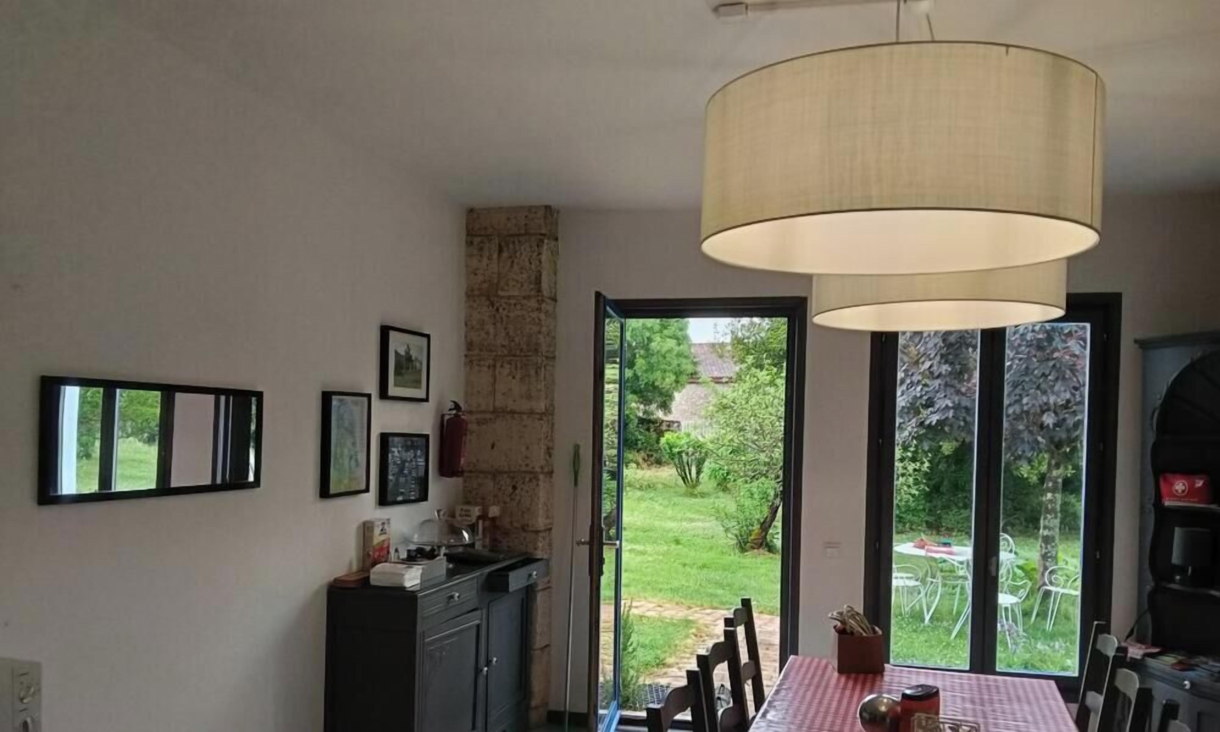 Comedor con mesa, sillas y vistas al jardín a través de puertas de cristal.