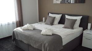 Una cama bien hecha con almohadas, una mesita de noche con una lámpara y un cuadro en la pared.
