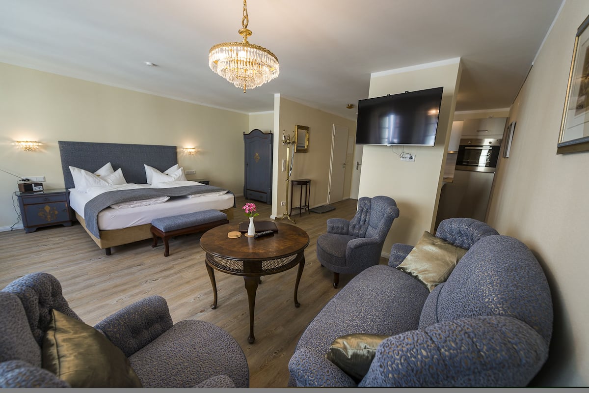 A hotel room with a bed, a TV, a dining table, and a sofa.
