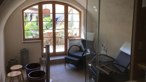 A sunlit room with a large arched window, wicker furniture, and a glass shower enclosure. - Appart.Bog2 (Görlitz)