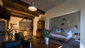 A modern living room with a wooden ceiling, a sofa, a dining table, and a bed with a white headboard. - Appart.Bog2 (Görlitz)