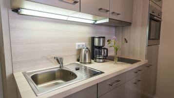 A modern kitchen with a stainless steel sink, a coffee maker, and a vase with flowers.