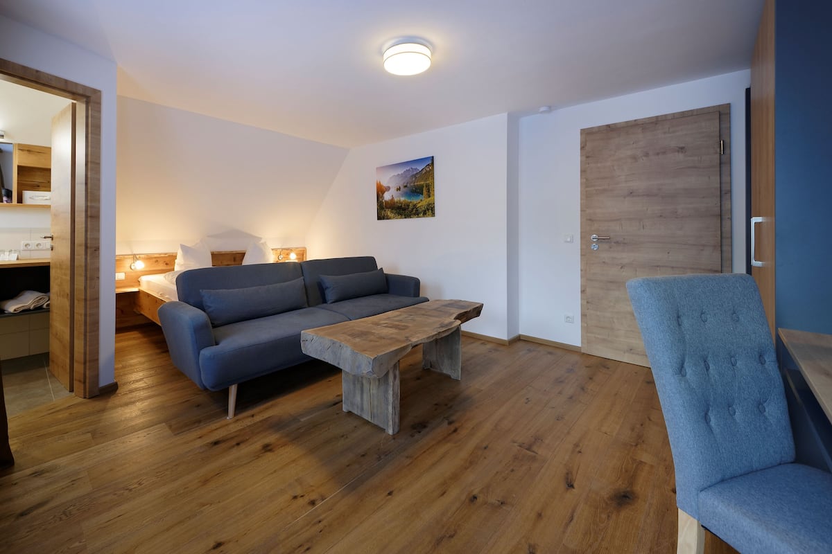 A living room with a wooden coffee table, a blue sofa, and a blue armchair.