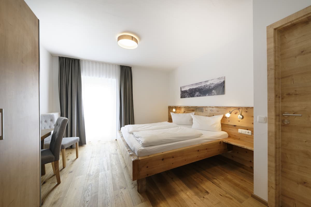 A bedroom with a wooden bed, a desk, and a chair.