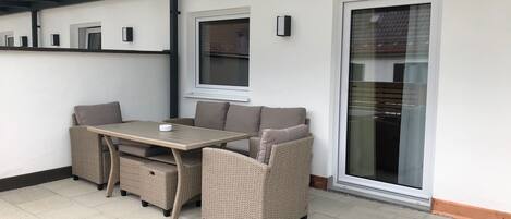A patio area with a table and chairs, a glass door, and a window.