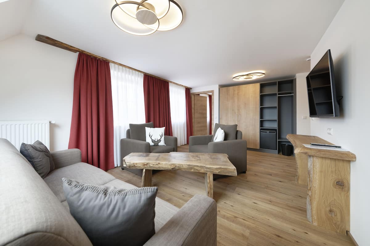 A modern living room with a wooden coffee table, grey sofas, and red curtains.