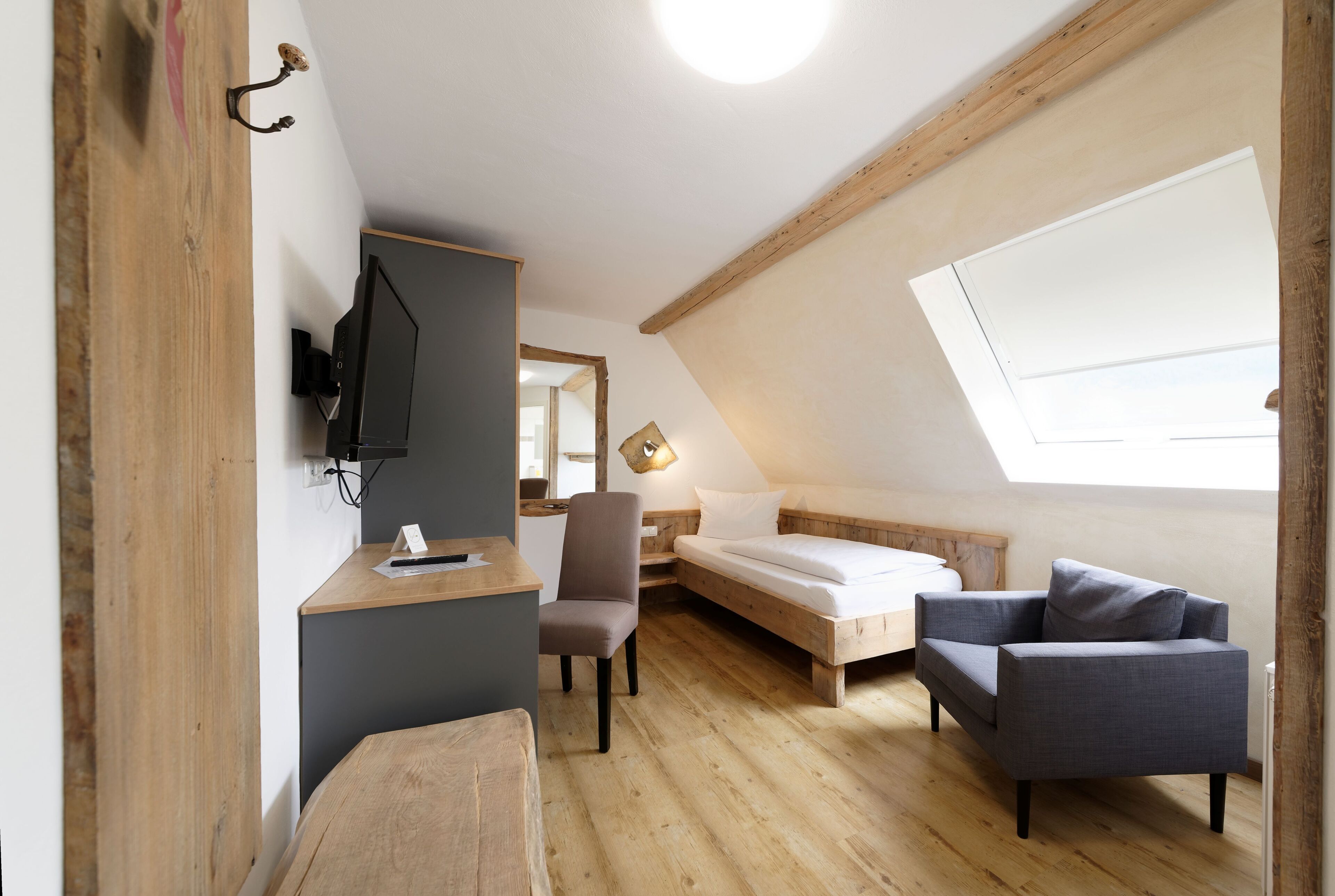 A cozy room with a desk, chair, bed, and a sofa.