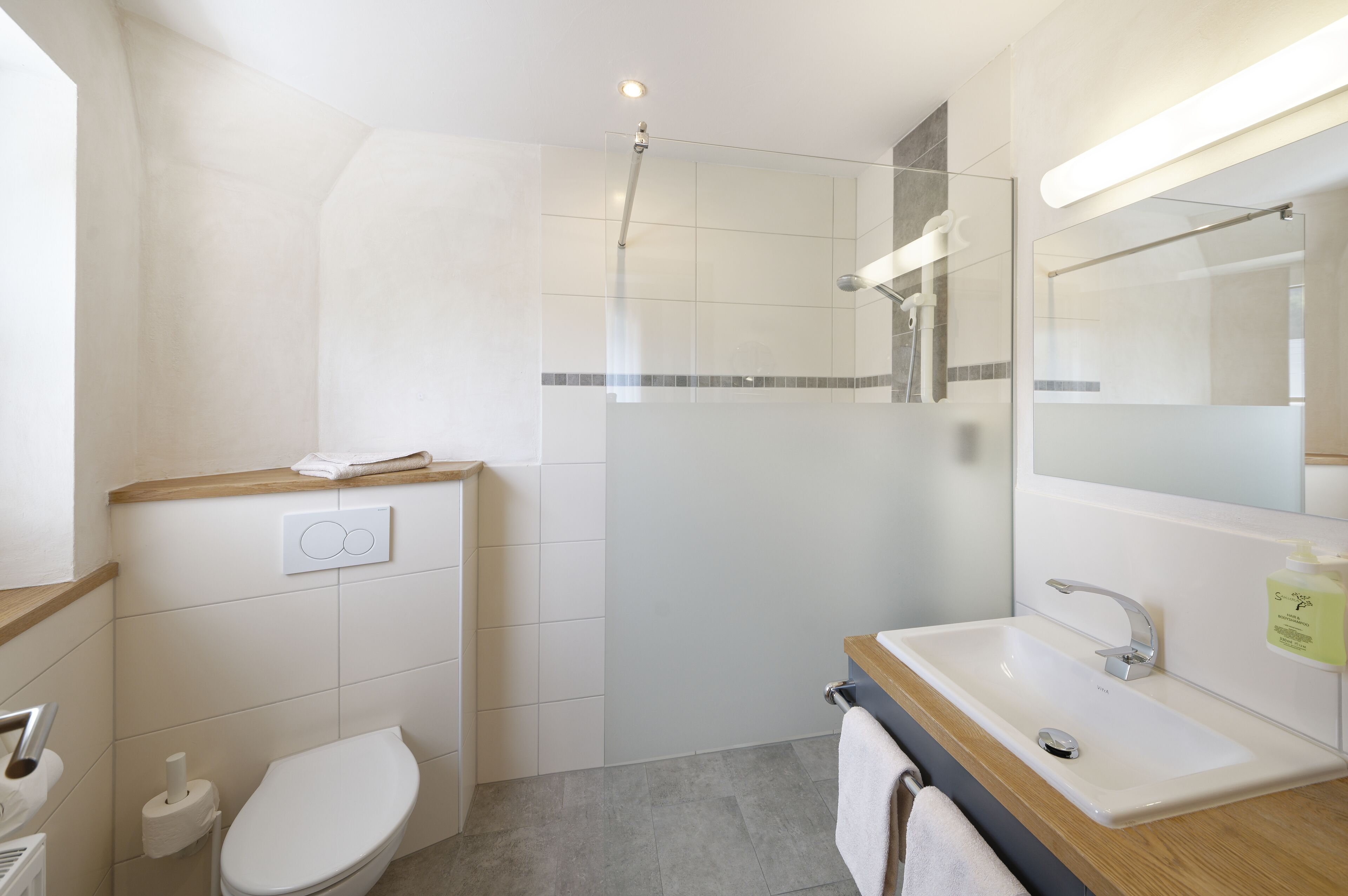 Un baño moderno con inodoro, lavabo y ducha.