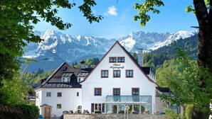 Un edificio blanco con un letrero que dice "Hotel Alpengrup" frente a un paisaje montañoso.