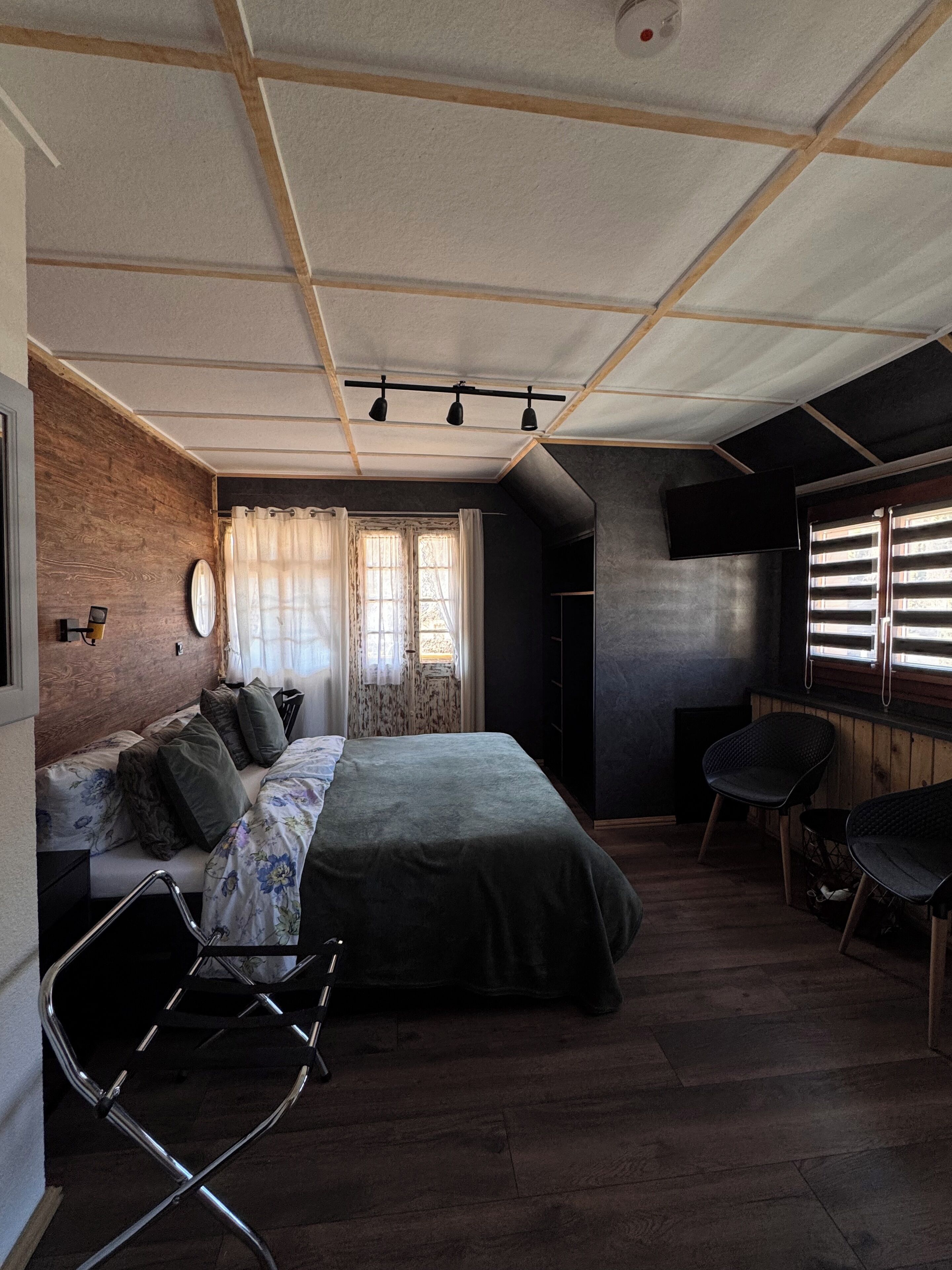 A bedroom with a bed, a chair, a desk, and a window with curtains.