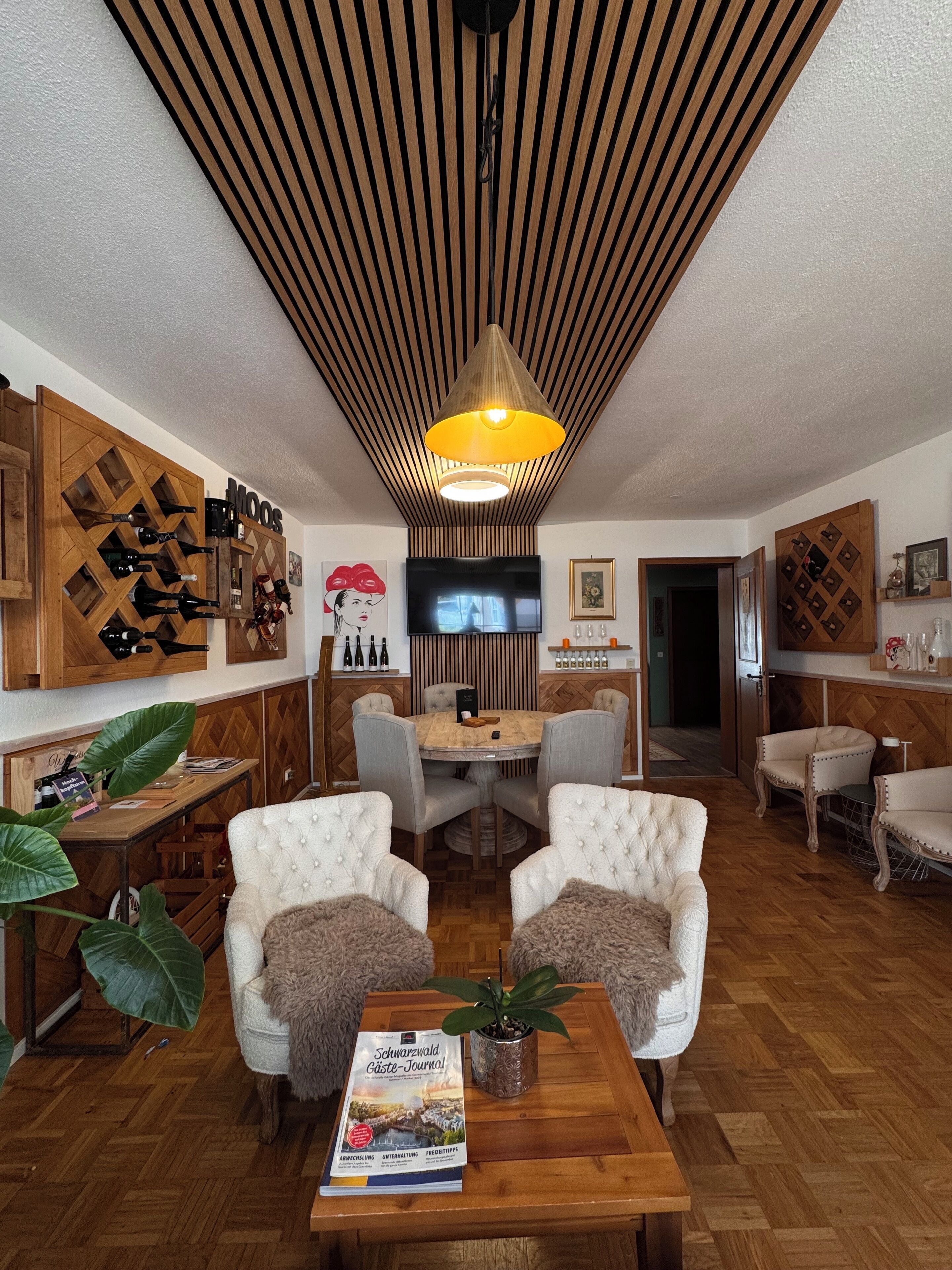 A cozy living room with a wooden ceiling, a round dining table, and comfortable seating.