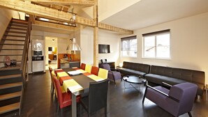 A spacious living area with a dining table, sofas, and a staircase leading to an upper level. - Freiraum Zentral (Garmisch-Partenkirchen)