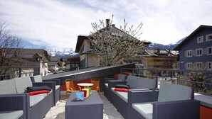 A rooftop terrace with wicker furniture, a table, and chairs. - Freiraum Zentral (Garmisch-Partenkirchen)