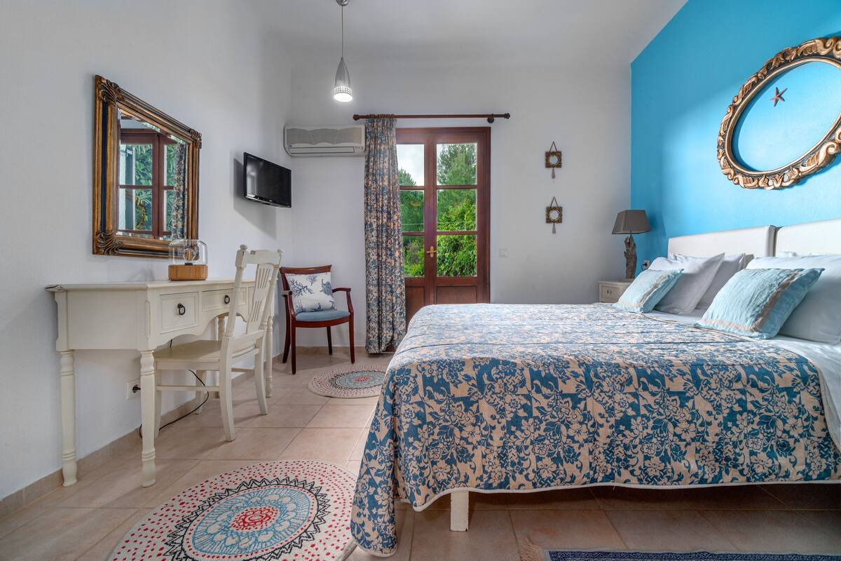 Un dormitorio con cama, escritorio, silla, televisor y ventana con cortinas.