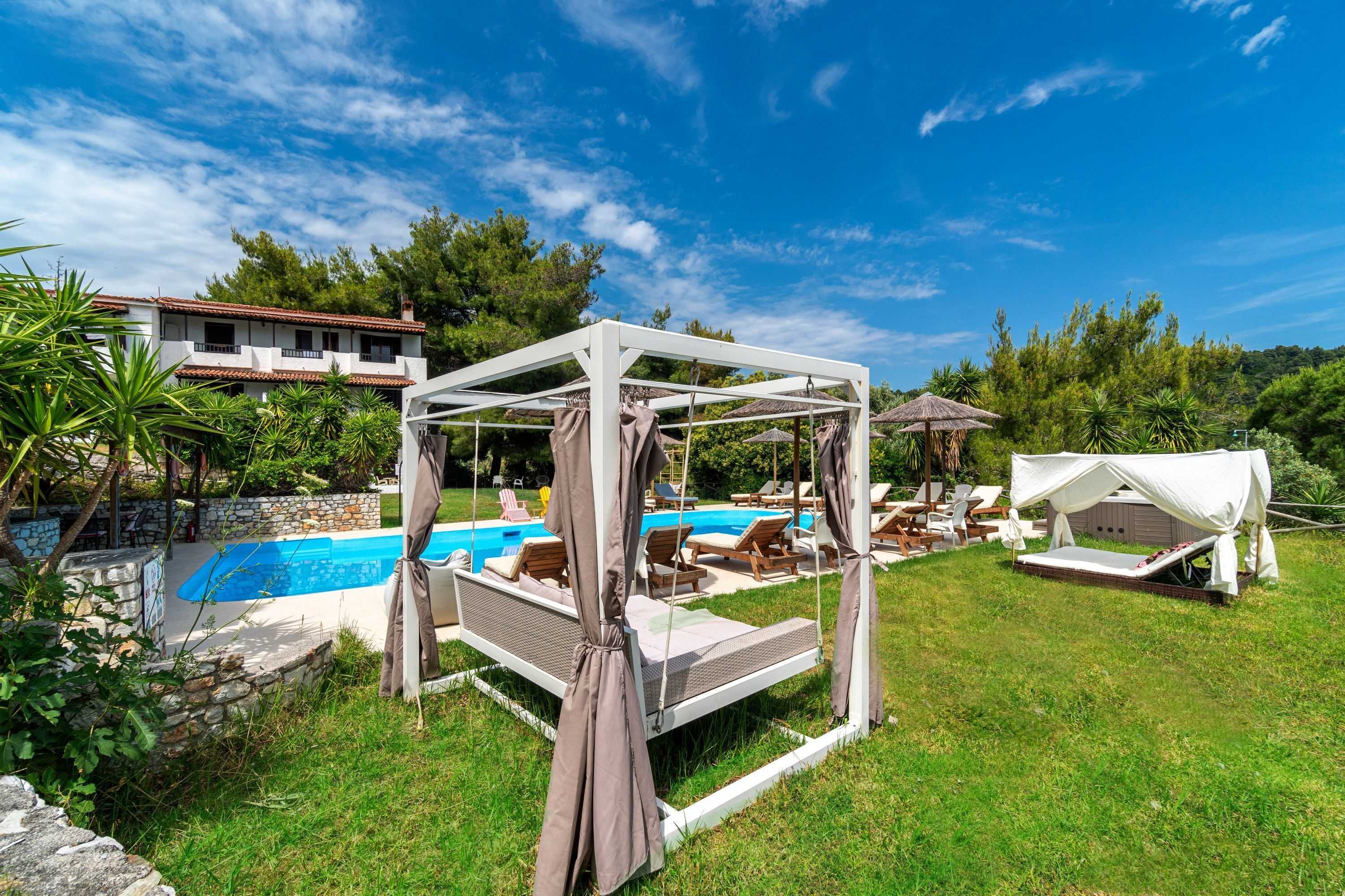 A poolside area with a canopy bed, lounge chairs, and a swimming pool.