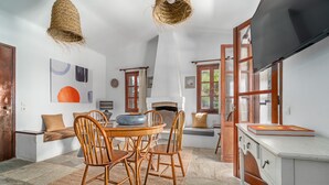 Un comedor con una mesa redonda y sillas, una chimenea y un televisor.
