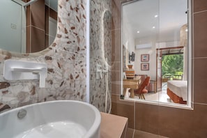 Une salle de bain dotée d’une grande baignoire, d’une douche et d’un espace de douche séparé par des parois en verre.