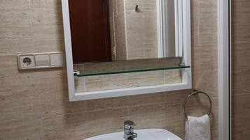 Driepersoonskamer | Badkamer | Een douche, een haardroger, handdoeken, zeep