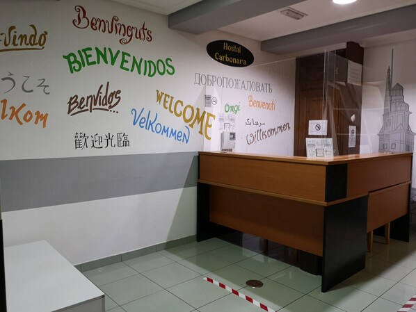 Una recepción con un tablón mostrando carteles de bienvenida en varios idiomas.