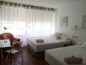 Una habitación de hotel con dos camas, una silla, una mesa y una lámpara.