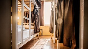 Una habitación con literas, una mesita y cortinas.