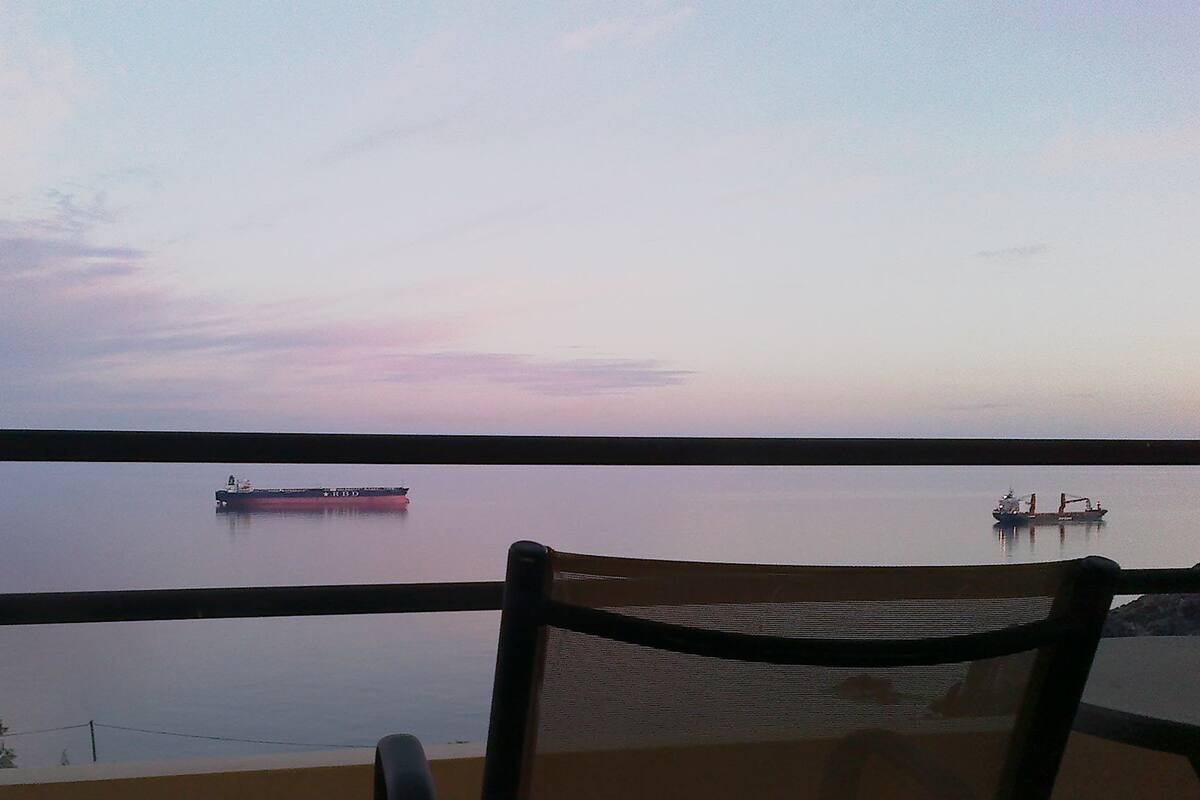 A view from a balcony overlooking calm water with two ships.