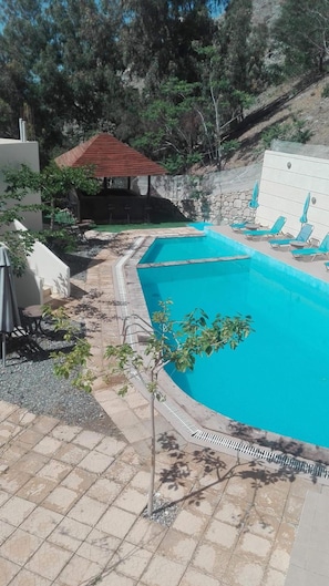A swimming pool with lounge chairs and a small pavilion.