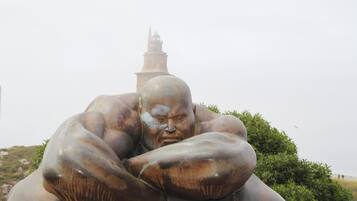 A large bronze statue of a muscular figure with a tower in the background.