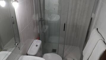 A modern bathroom with a glass-enclosed shower, a white sink, and a toilet.