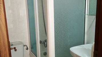 Un baño con inodoro, cabina de ducha y lavamanos.