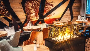 Un intérieur chaleureux avec des poutres en bois, des tables rondes et des sièges confortables.