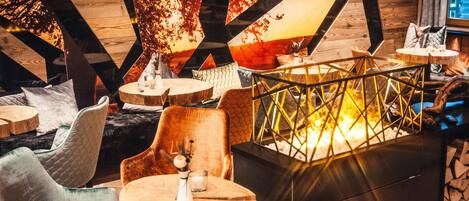 A cozy interior with wooden beams, round tables, and comfortable seating.