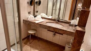Ein Badezimmer mit Waschbecken, Spiegel, Handtuchhalter und Duschbereich.