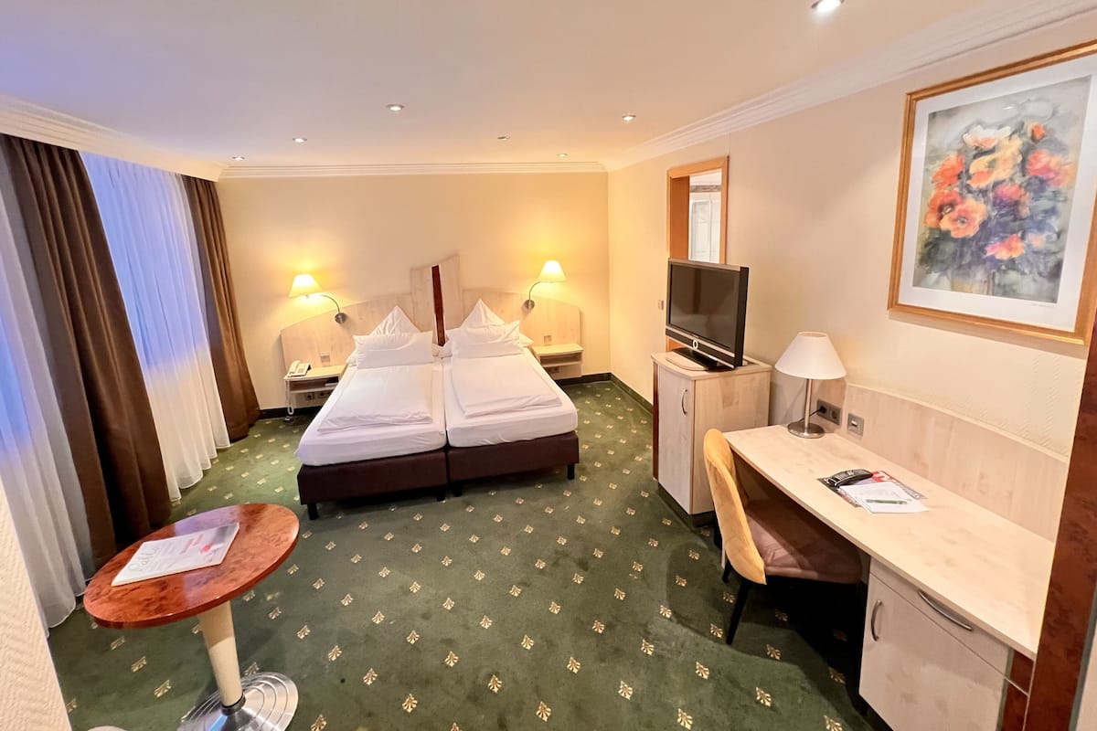 Une chambre d’hôtel avec un lit, un bureau, une chaise et une petite table.