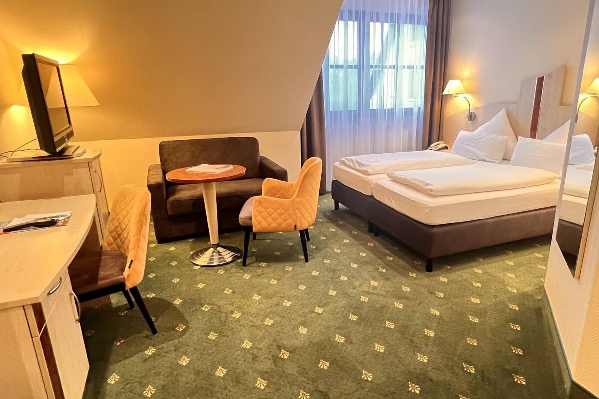 Une chambre d’hôtel comprenant un lit, un bureau, une chaise, une petite table et un téléviseur.