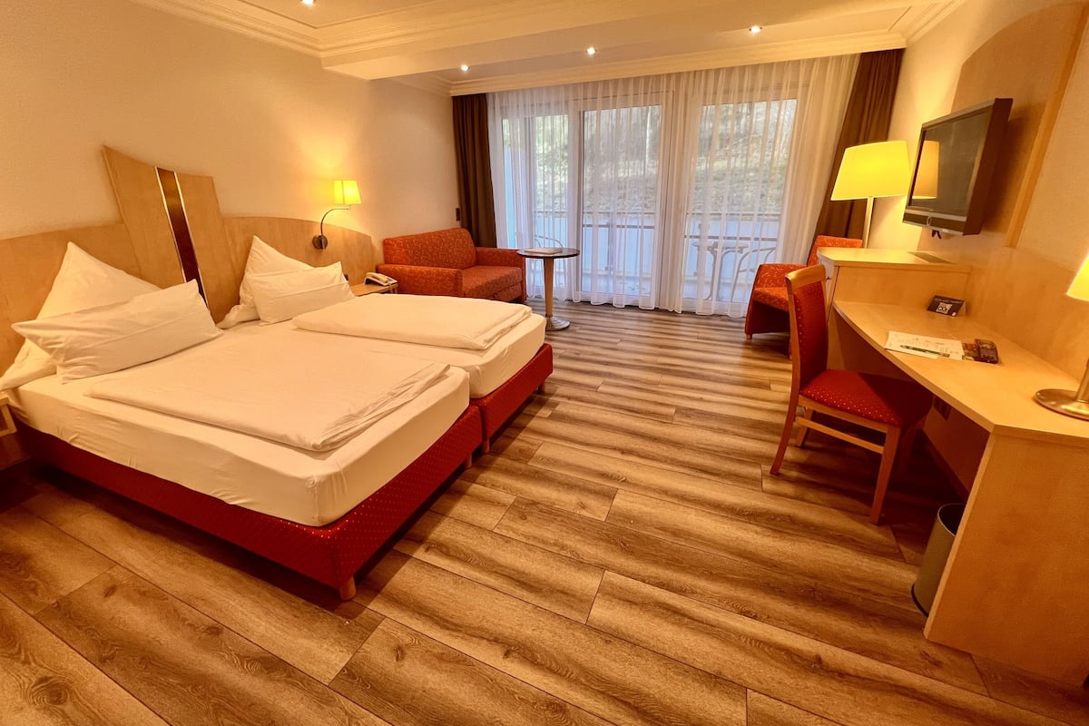 Une chambre d’hôtel avec un lit double, un bureau, une chaise, une petite table et un téléviseur.