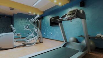 A fitness room with a treadmill, elliptical, and exercise balls.