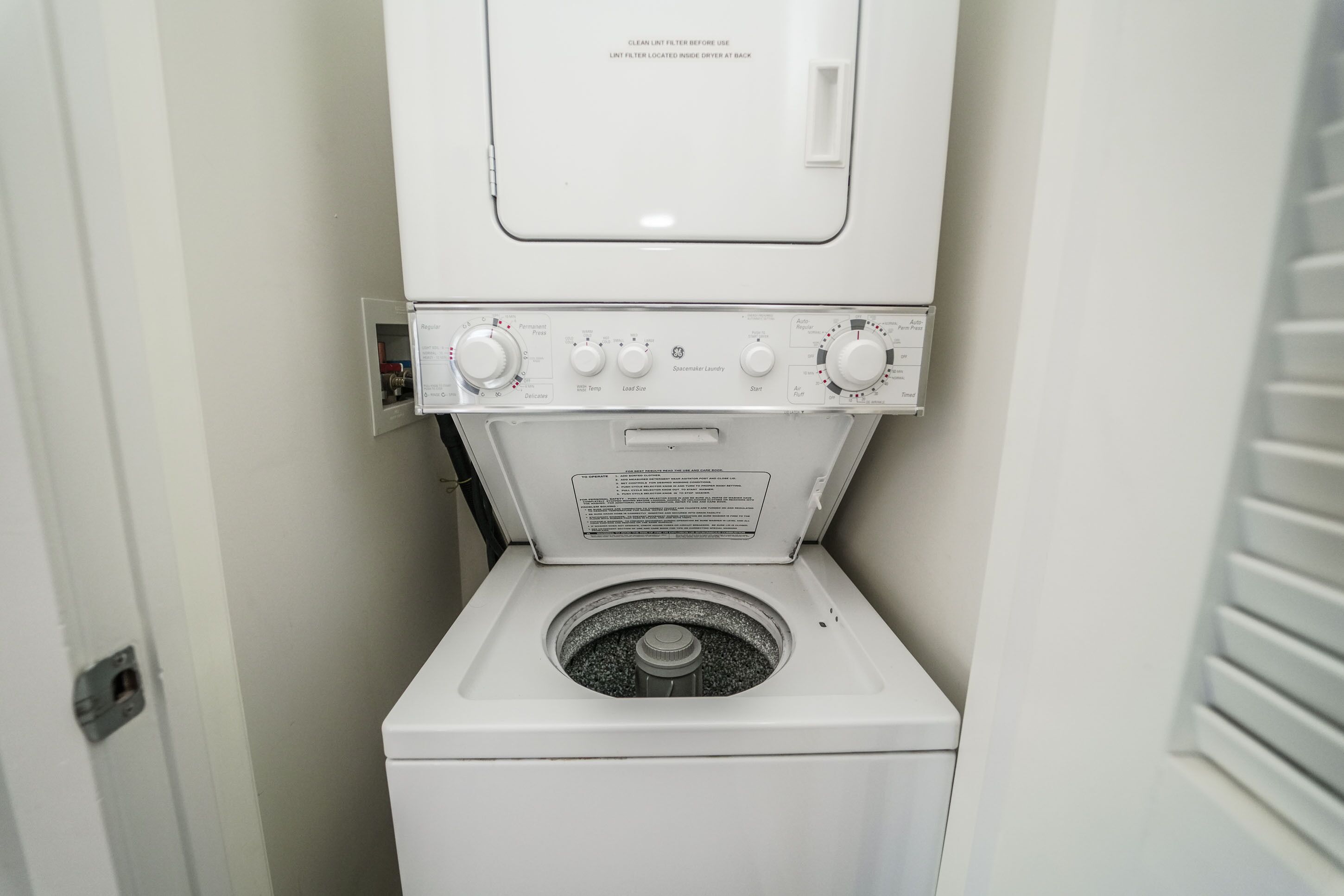 A front-loading washing machine with control knobs and a label.