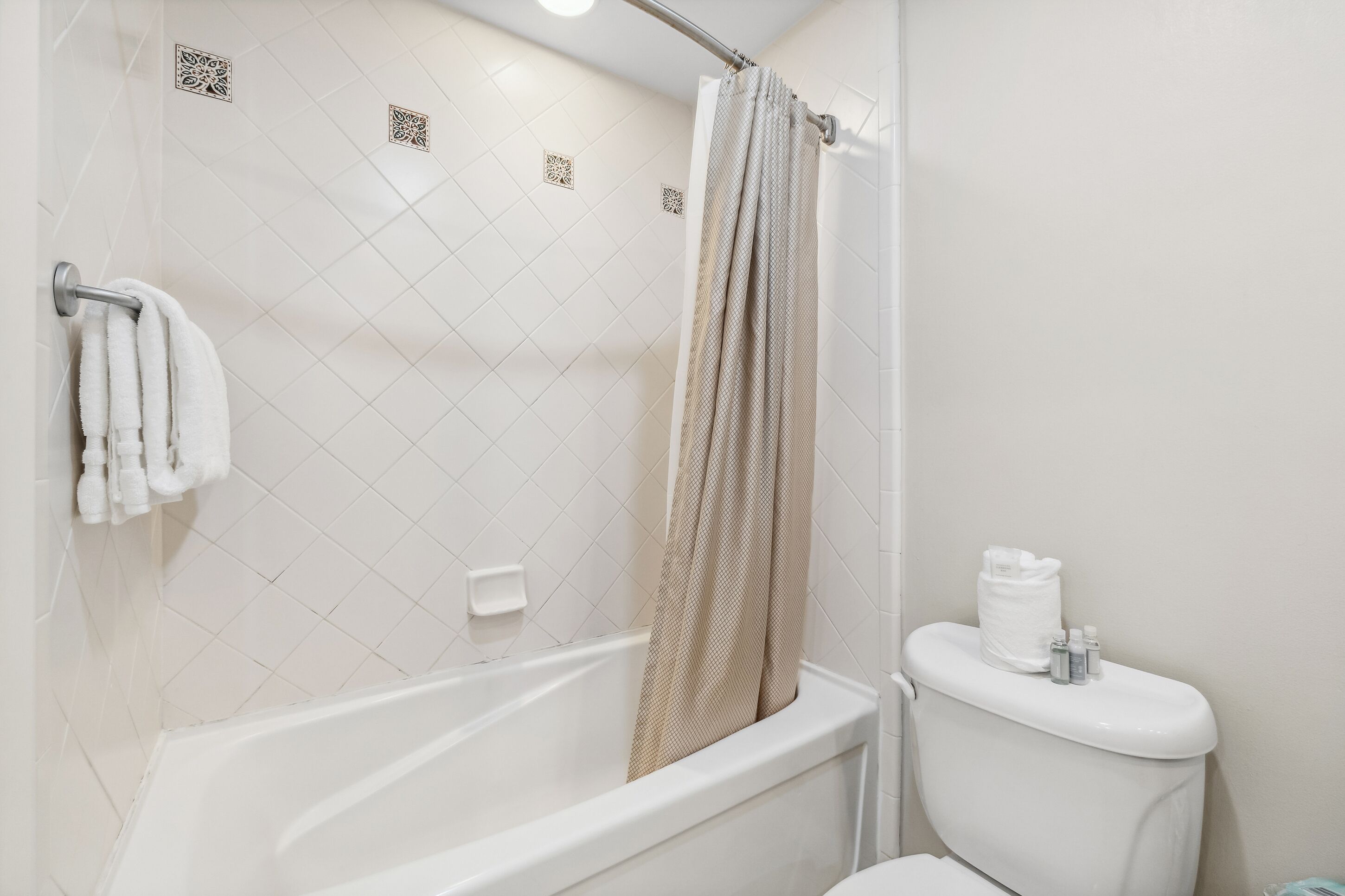 A bathroom with a bathtub, toilet, and shower curtain.