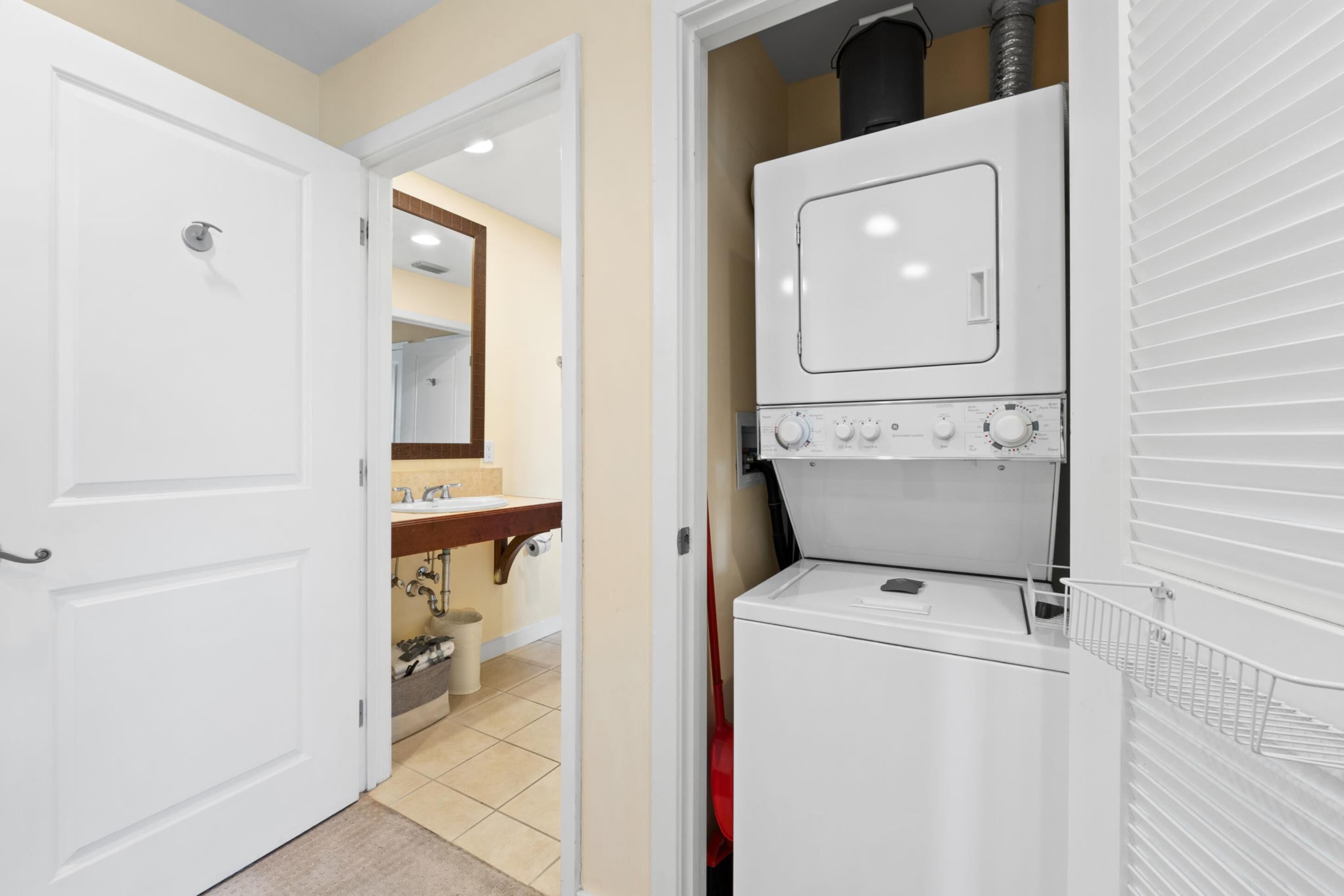 A laundry room with a washer and dryer, a sink, and a mirror.
