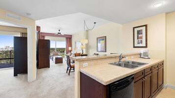 A hotel room with a kitchen area, a dining area with a view, and a balcony.