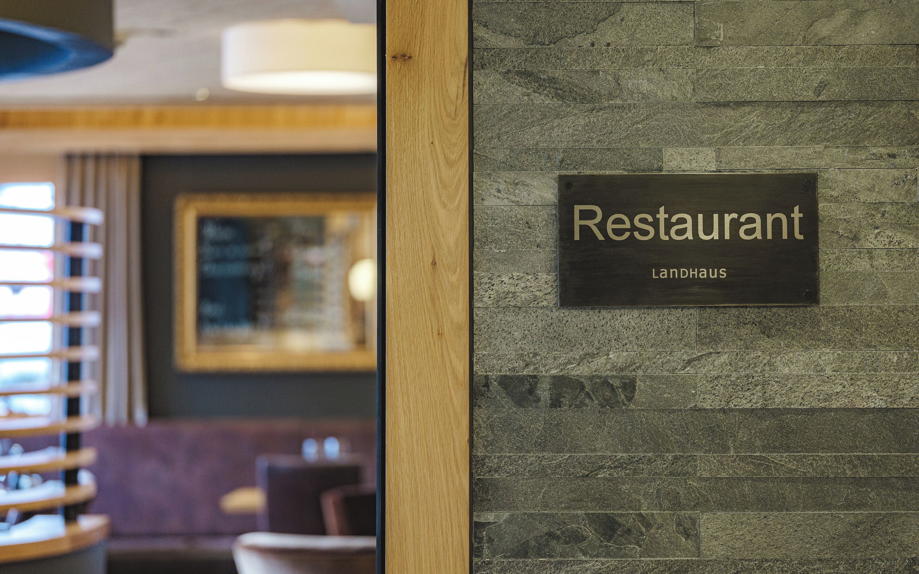 Een restaurantbord met de naam 'Landhaus' op een structuurwand.