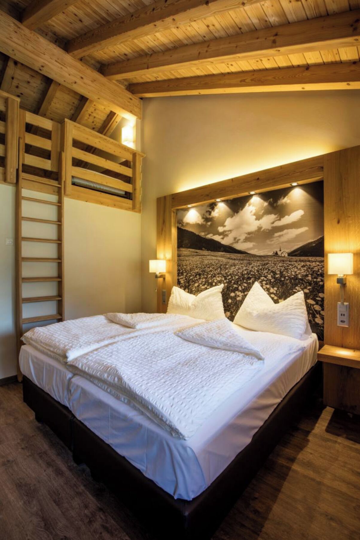 Ein Bett mit Kopfteil, einer Holzleiter und einer Wandleuchte.