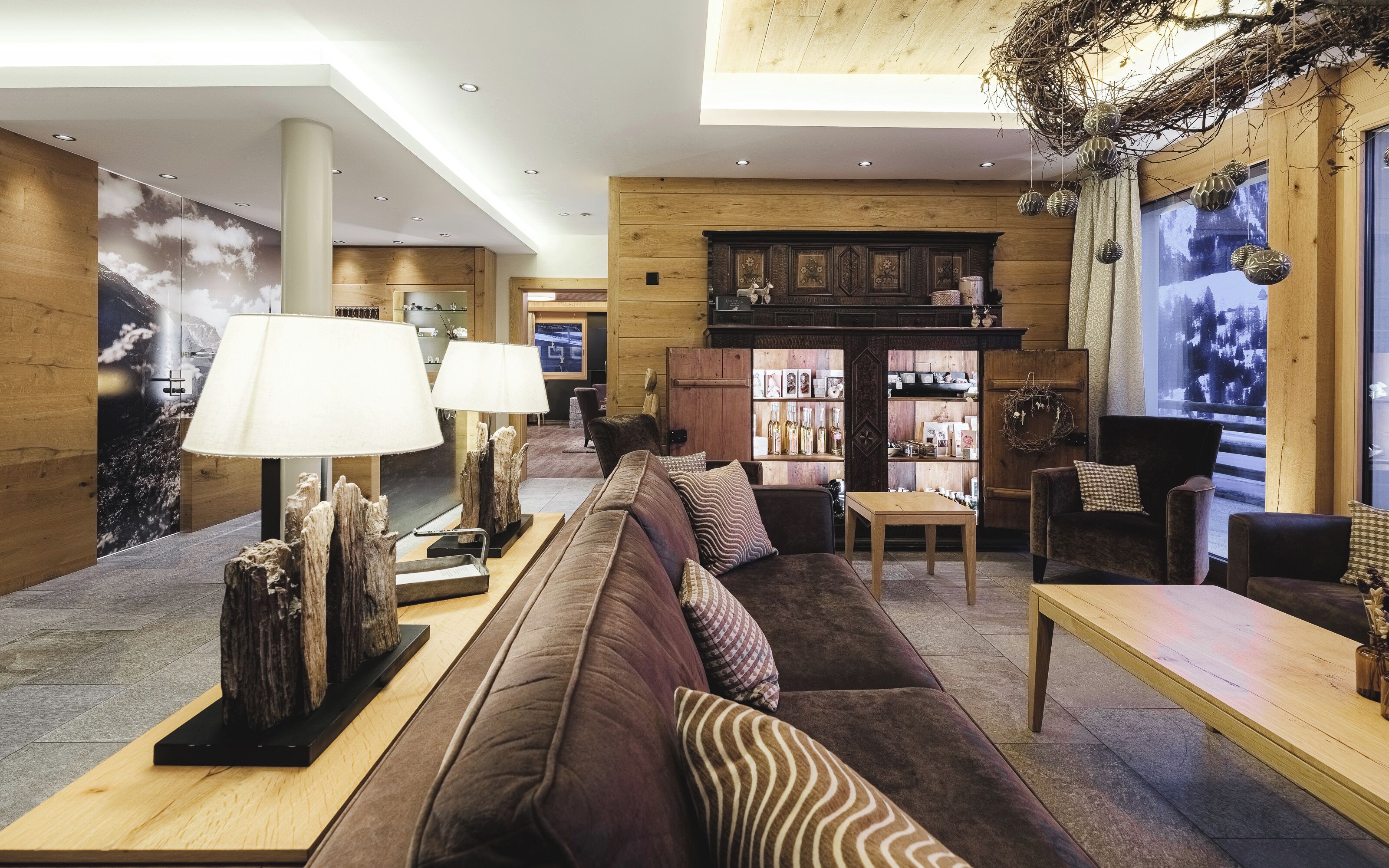 A modern interior with a wooden accent wall, a sofa set, a coffee table, and a decorative wall with hanging ornaments.