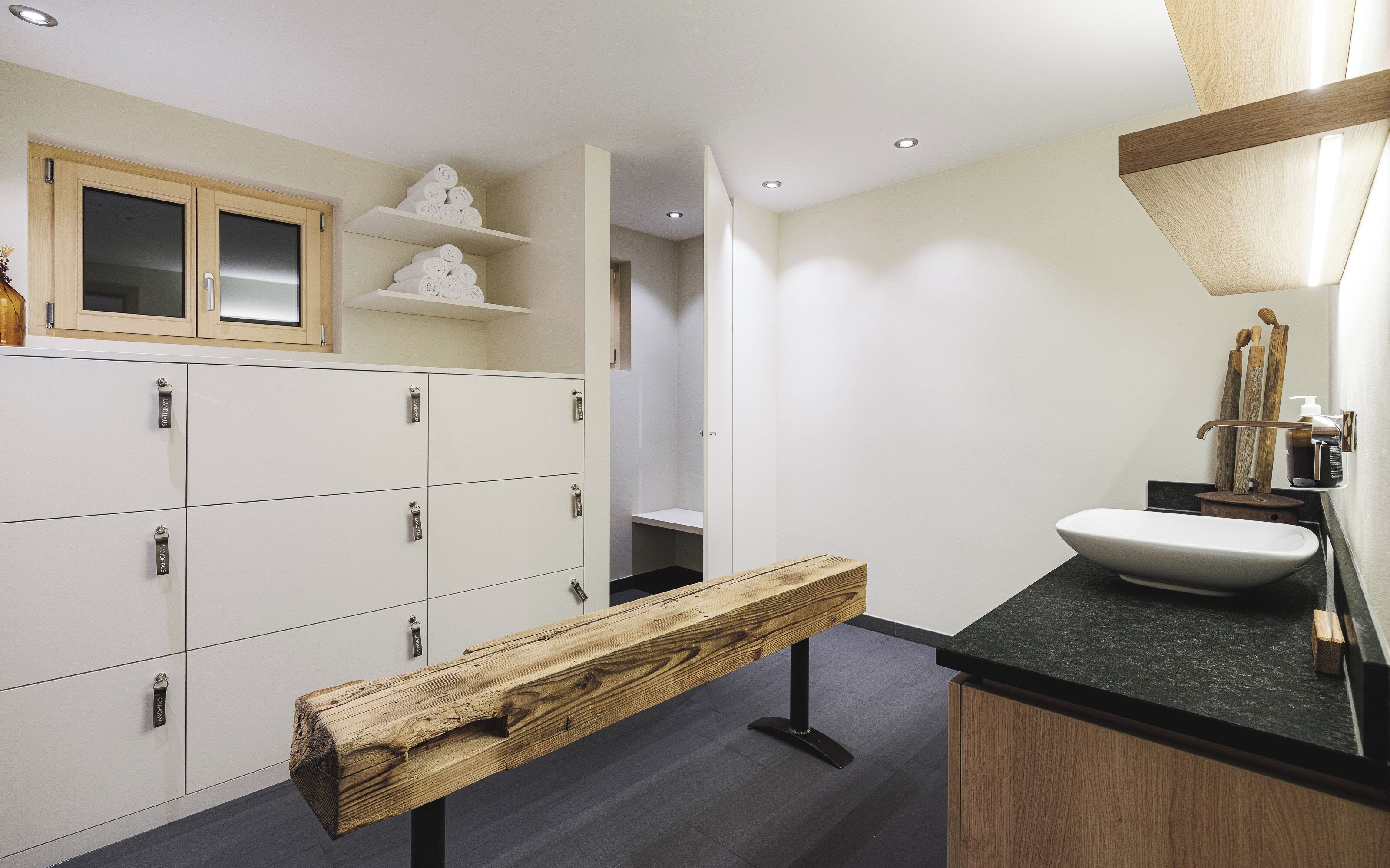A bathroom with a wooden bench, a sink, and a mirror.