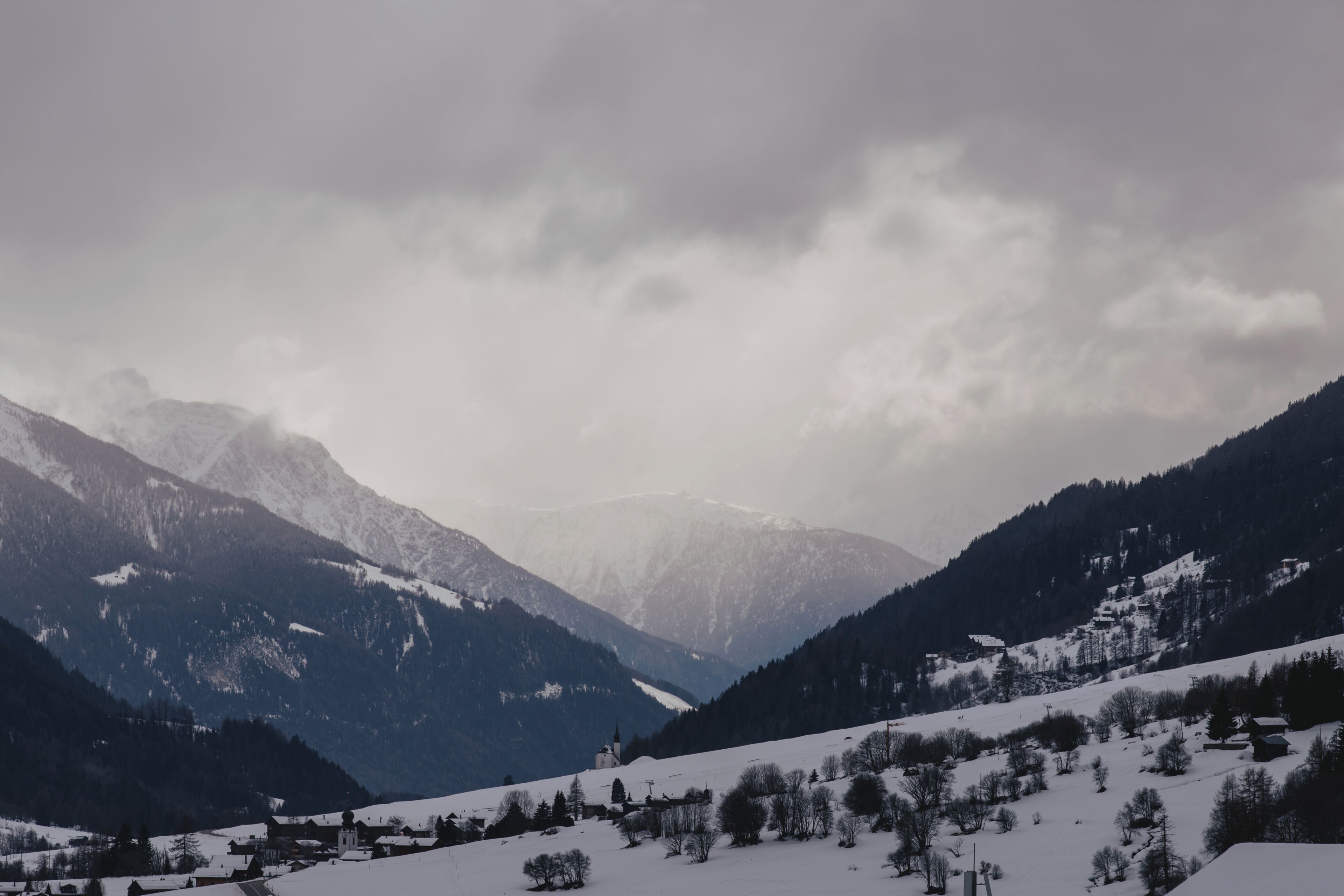 Un paisaje montañoso cubierto de nieve, con un pequeño pueblo y una iglesia.