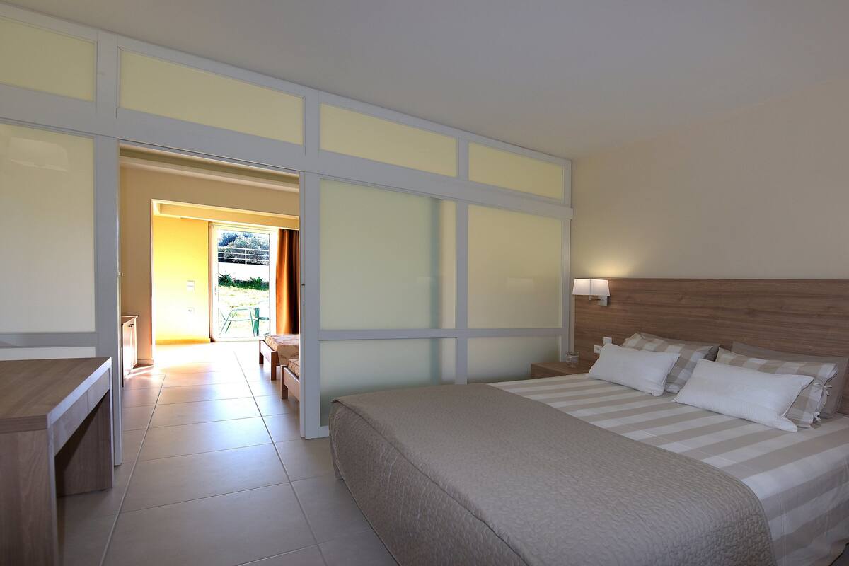 Ein Hotelzimmer mit Bett, Nachttischen und Blick nach draußen.