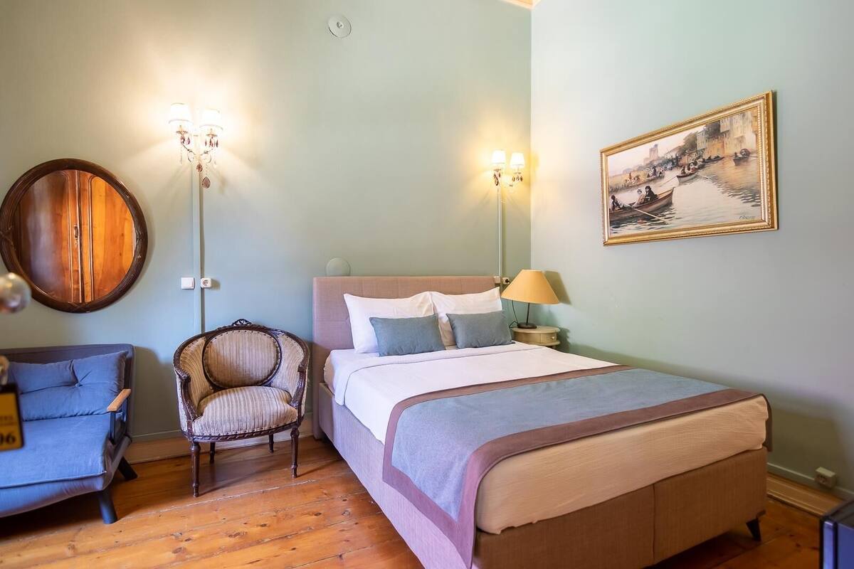 Une chambre à coucher comprenant un lit, une chaise, une table de chevet et une lampe fixée au mur.