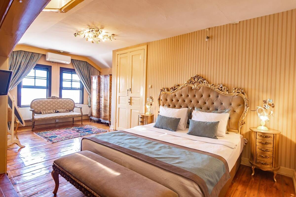 Une chambre spacieuse avec un grand lit, un coin salon avec un canapé et un plancher en bois.