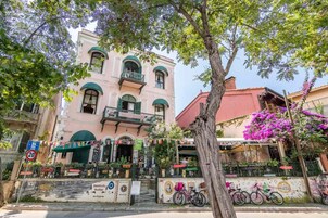 Un edificio con balcón, una bicicleta estacionada frente a él y un árbol con flores púrpuras.